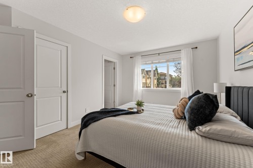 Carpeted bedroom featuring a large window, a flush mount ceiling light, and two-panel interior doors with brushed nickel hardware - #18 7289 South Terwillegar Dr Nw, Edmonton, AB - Indoor Photo Showing Bedroom