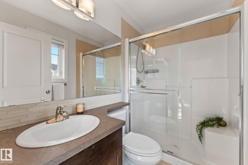 Bathroom featuring a built-in vanity with an undermount sink, a tiled backsplash, and a glass-enclosed shower with a built-in seat - #18 7289 South Terwillegar Dr Nw, Edmonton, AB - Indoor Photo Showing Bathroom