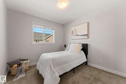 Bright room featuring a window with white trim, light gray walls, and textured carpet flooring - #18 7289 South Terwillegar Dr Nw, Edmonton, AB - Indoor Photo Showing Bedroom
