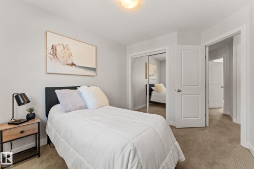 Carpeted room featuring a double-paneled interior door and a bi-fold mirrored closet door - #18 7289 South Terwillegar Dr Nw, Edmonton, AB - Indoor Photo Showing Bedroom