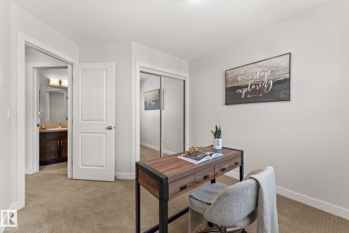 Neutral-toned room featuring a doorway to a bathroom with a dark wood vanity, a second doorway, and a mirrored closet - #18 7289 South Terwillegar Dr Nw, Edmonton, AB - Indoor Photo Showing Other Room