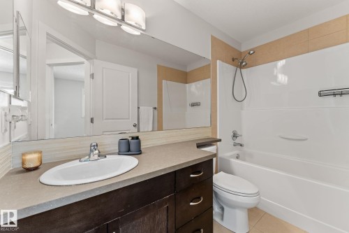 Bathroom featuring a dark wood-finish vanity with an integrated sink, a full-width mirror, and a wall-mounted light fixture - #18 7289 South Terwillegar Dr Nw, Edmonton, AB - Indoor Photo Showing Bathroom