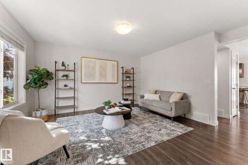 Bright living area featuring wood-finish flooring, white trim, and a window with natural light - #18 7289 South Terwillegar Dr Nw, Edmonton, AB - Indoor Photo Showing Living Room