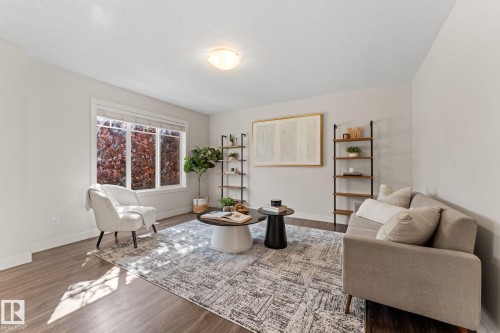 Spacious interior room featuring wood-finish flooring, a large window, a ceiling-mounted light fixture, and light-toned wall finishes - #18 7289 South Terwillegar Dr Nw, Edmonton, AB - Indoor Photo Showing Living Room