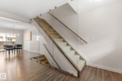 Modern staircase featuring glass panel railings, wood-finish handrails, and neutral-toned carpeted treads - #18 7289 South Terwillegar Dr Nw, Edmonton, AB - Indoor Photo Showing Other Room