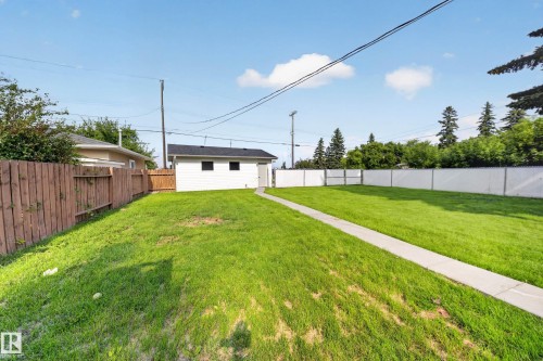 Expansive green lawn with a concrete pathway leading to a detached white structure - 5204 97A Avenue Nw, Edmonton, AB - Outdoor With Backyard