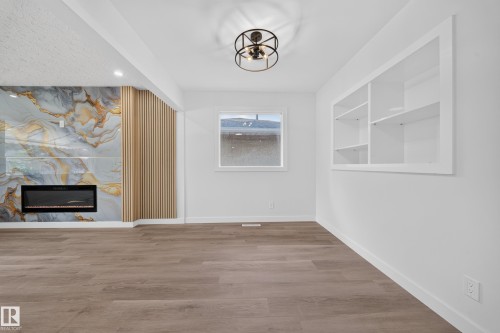 Feature wall with a large electric fireplace and wood slat detailing - 5204 97A Avenue Nw, Edmonton, AB - Indoor Photo Showing Other Room
