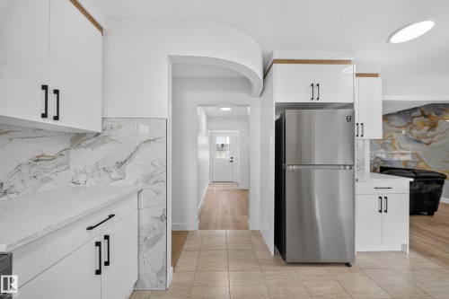 Kitchen featuring white cabinetry, quartz countertops, and a patterned backsplash - 5204 97A Avenue Nw, Edmonton, AB - Indoor Photo Showing Kitchen