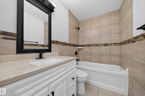 Bathroom featuring a white vanity with a light-toned countertop, an integrated sink, and black fixtures - 5204 97A Avenue Nw, Edmonton, AB - Indoor Photo Showing Bathroom