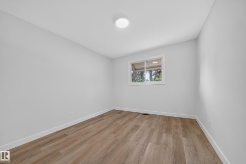 Light-filled interior space featuring wood-finish flooring, white baseboards, and a flush-mount ceiling light fixture - 5204 97A Avenue Nw, Edmonton, AB - Indoor Photo Showing Other Room