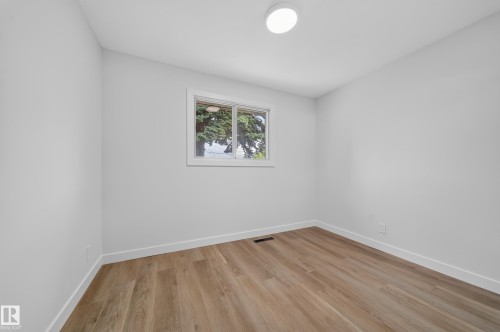 Room featuring wood-finish flooring, white baseboards, and a single window with white trim - 5204 97A Avenue Nw, Edmonton, AB - Indoor Photo Showing Other Room