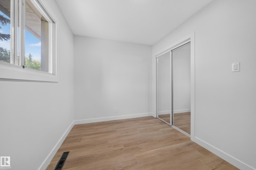 Bright interior room featuring wood-finish flooring, white walls, and a large window - 5204 97A Avenue Nw, Edmonton, AB - Indoor Photo Showing Other Room