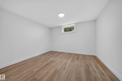 Spacious room featuring wood-finish flooring, white baseboards, and neutral wall paint - 5204 97A Avenue Nw, Edmonton, AB - Indoor Photo Showing Other Room