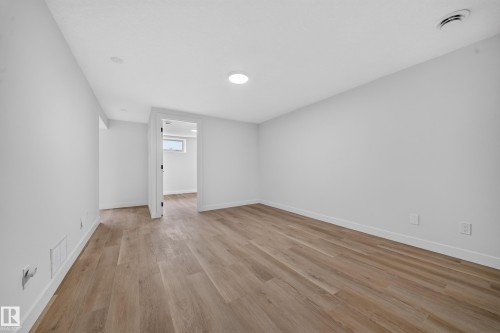 Spacious room featuring wood-finish flooring, recessed ceiling lighting, a white painted baseboard, and a white painted wall finish - 5204 97A Avenue Nw, Edmonton, AB - Indoor Photo Showing Other Room