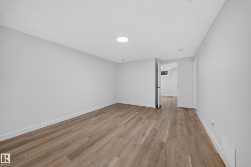 Spacious room featuring wood-finish flooring, white walls, recessed ceiling lighting, and crisp white trim - 5204 97A Avenue Nw, Edmonton, AB - Indoor Photo Showing Other Room