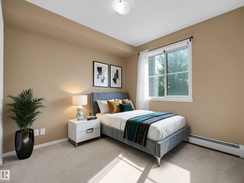 Carpeted room with a large window, neutral wall paint, and a built-in baseboard heater - #109 3207 James Mowatt Tr Sw, Edmonton, AB - Indoor Photo Showing Bedroom