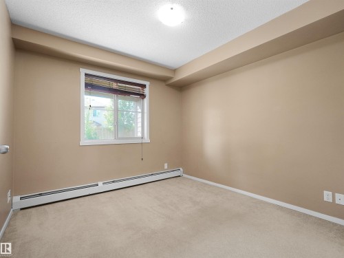 Carpeted room featuring neutral wall tones, a double-paned window with wood blinds, baseboard heating, a flush-mount ceiling light, and white trim - #109 3207 James Mowatt Tr Sw, Edmonton, AB - Indoor Photo Showing Other Room