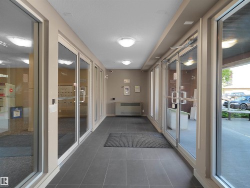 Corridor featuring tile flooring, multiple glass doors, and recessed ceiling lights - #109 3207 James Mowatt Tr Sw, Edmonton, AB - Indoor Photo Showing Other Room