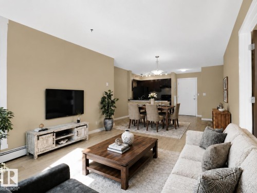 Open-concept living space featuring wood-finish flooring, recessed lighting, and a neutral wall palette - #109 3207 James Mowatt Tr Sw, Edmonton, AB - Indoor Photo Showing Living Room