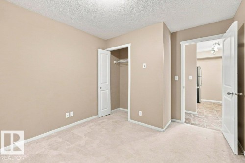 Neutral-toned interior room with light-colored carpeting, a built-in closet with bifold doors, and white baseboards - #119 111 Watt Cm Sw, Edmonton, AB - Indoor Photo Showing Other Room