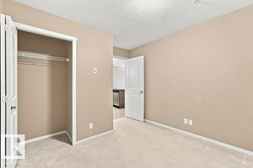 Neutral tone walls and carpeting throughout, featuring a bi-fold closet with wire shelving - #119 111 Watt Cm Sw, Edmonton, AB - Indoor Photo Showing Other Room