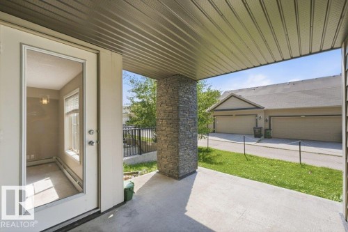 Covered concrete patio featuring a stone-clad column and overhead paneling - #119 111 Watt Cm Sw, Edmonton, AB - Outdoor With Deck Patio Veranda With Exterior