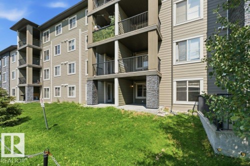 Multi-story building exterior featuring horizontal siding and stone veneer accents - #119 111 Watt Cm Sw, Edmonton, AB - Outdoor With Facade