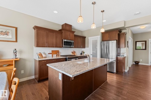 Kitchen featuring a central island with a light-toned countertop and dual pendant lights - 3413 Cameron Heights Cove Nw, Edmonton, AB - Indoor Photo Showing Kitchen With Upgraded Kitchen