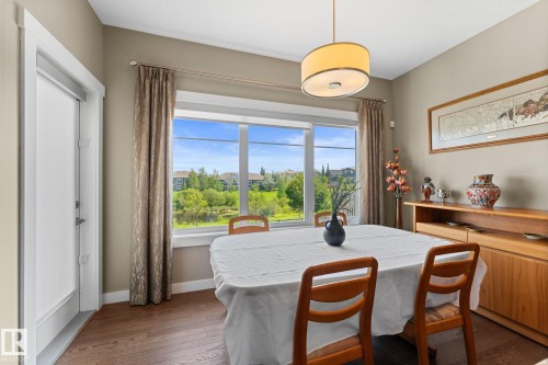 Dining area featuring wood-finish flooring, a contemporary drum pendant light, and a large picture window - 3413 Cameron Heights Cove Nw, Edmonton, AB - Indoor Photo Showing Dining Room