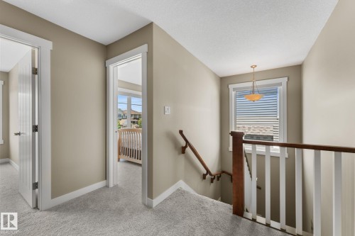 Upper landing with light gray carpeting, white trim, and a warm neutral wall color - 3413 Cameron Heights Cove Nw, Edmonton, AB - Indoor Photo Showing Other Room