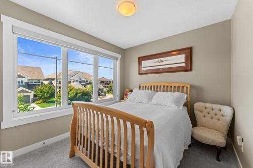 Bedroom featuring a three-panel window, light-colored walls, carpeted flooring, and a ceiling-mounted light fixture - 3413 Cameron Heights Cove Nw, Edmonton, AB - Indoor Photo Showing Bedroom