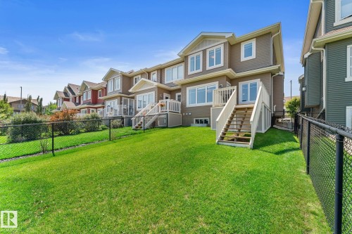 Spacious rear yard with green grass, private chain link fencing, and a multi-level deck with stairs leading to the ground - 3413 Cameron Heights Cove Nw, Edmonton, AB - Outdoor With Deck Patio Veranda