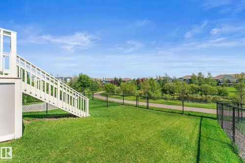 Expansive green lawn with a white exterior staircase providing access to an upper level - 3413 Cameron Heights Cove Nw, Edmonton, AB - Outdoor