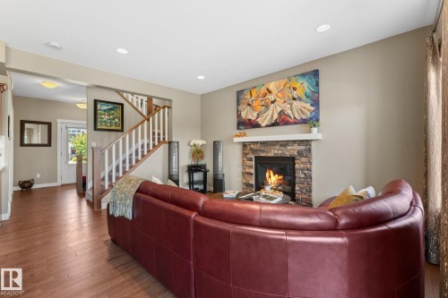 Living area featuring a stone-clad fireplace with a white mantel, recessed lighting, and wood-finish flooring - 3413 Cameron Heights Cove Nw, Edmonton, AB - Indoor Photo Showing Living Room With Fireplace