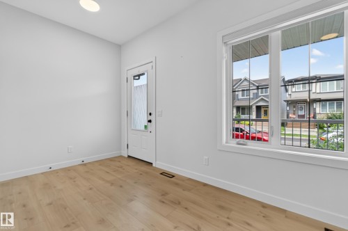 Spacious room featuring wood-finish flooring, white baseboards, and a large window - 1534 Plum Circle Circle Sw, Edmonton, AB - Indoor Photo Showing Other Room