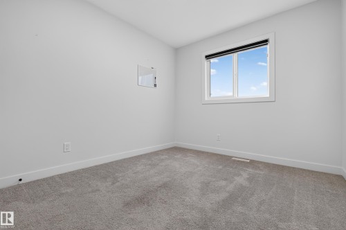 Carpeted room featuring a white-framed window with a black roller shade, light gray walls, and white baseboards - 1534 Plum Circle Circle Sw, Edmonton, AB - Indoor Photo Showing Other Room