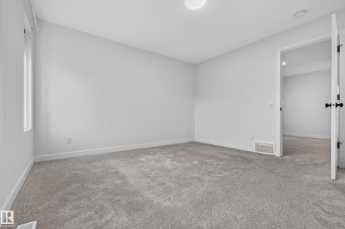 Bedroom featuring light gray carpeting, white walls, a single window, and a white interior door with black hardware - 1534 Plum Circle Circle Sw, Edmonton, AB - Indoor Photo Showing Other Room