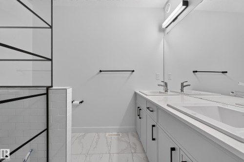 Dual vanity with under-mount sinks, a continuous mirror, and integrated lighting - 1534 Plum Circle Circle Sw, Edmonton, AB - Indoor