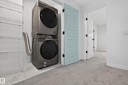 Dedicated laundry area featuring a stacked washer and dryer, white wire shelving, and white tile flooring - 1534 Plum Circle Circle Sw, Edmonton, AB - Indoor Photo Showing Laundry Room
