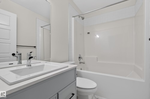 Bathroom featuring a white vanity with a rectangular undermount sink, chrome faucet, and a large wall-mounted mirror - 1534 Plum Circle Circle Sw, Edmonton, AB - Indoor Photo Showing Bathroom