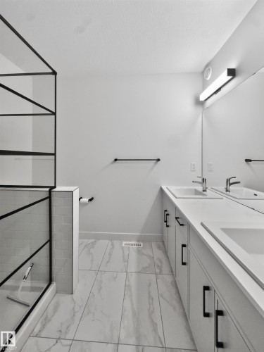 Dual vanity with integrated sinks, contemporary matte black hardware, and an expansive mirror - 1534 Plum Circle Circle Sw, Edmonton, AB - Indoor