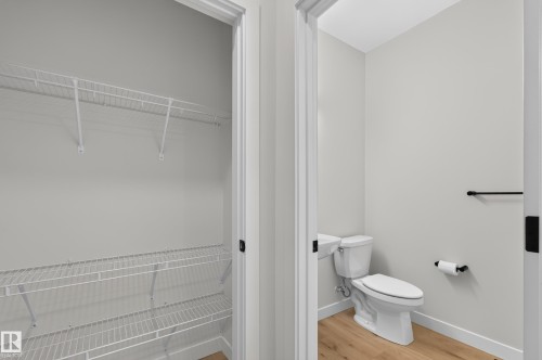 Powder room with wood-finish flooring, white walls, and matte black hardware - 1534 Plum Circle Circle Sw, Edmonton, AB - Indoor Photo Showing Bathroom