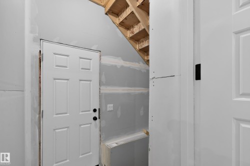 Six-panel interior door with matte black hardware, unfinished drywall, and exposed wood framing - 1534 Plum Circle Circle Sw, Edmonton, AB - Indoor Photo Showing Other Room