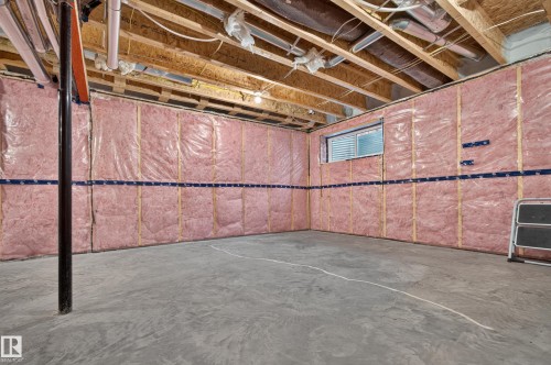 Unfinished basement featuring insulated walls, exposed ceiling joists and utilities, a concrete floor, and a single window with horizontal blinds - 1534 Plum Circle Circle Sw, Edmonton, AB - Indoor Photo Showing Basement