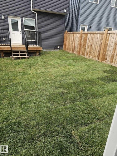Expansive green lawn providing outdoor space, bordered by a natural wood fence - 1534 Plum Circle Circle Sw, Edmonton, AB - Outdoor