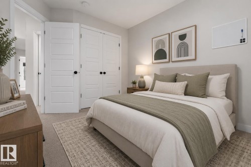 Bedroom featuring neutral wall paint, carpet flooring, multiple white paneled doors with black hardware, and a built-in closet - 1534 Plum Circle Circle Sw, Edmonton, AB - Indoor Photo Showing Bedroom