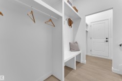 Entryway featuring built-in storage, a bench with cubbies, white paneling, and wood-finish flooring - 