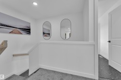 Staircase featuring grey carpeting and a natural wood handrail - 
