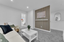 Carpeted living area featuring a decorative slat wall with an integrated shelf, recessed ceiling lighting, and crisp white walls - 
