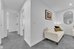 Hallway featuring light gray carpeting, white baseboards, and matte black door hardware - 